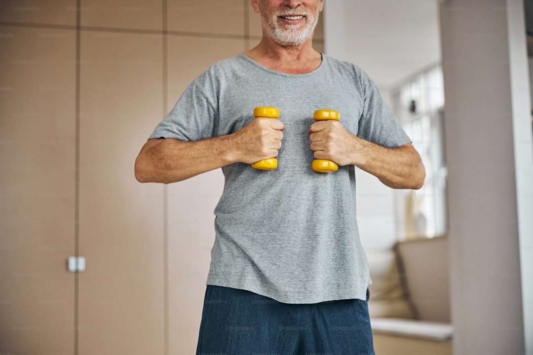 Grey haired man holding dumbbells while working out