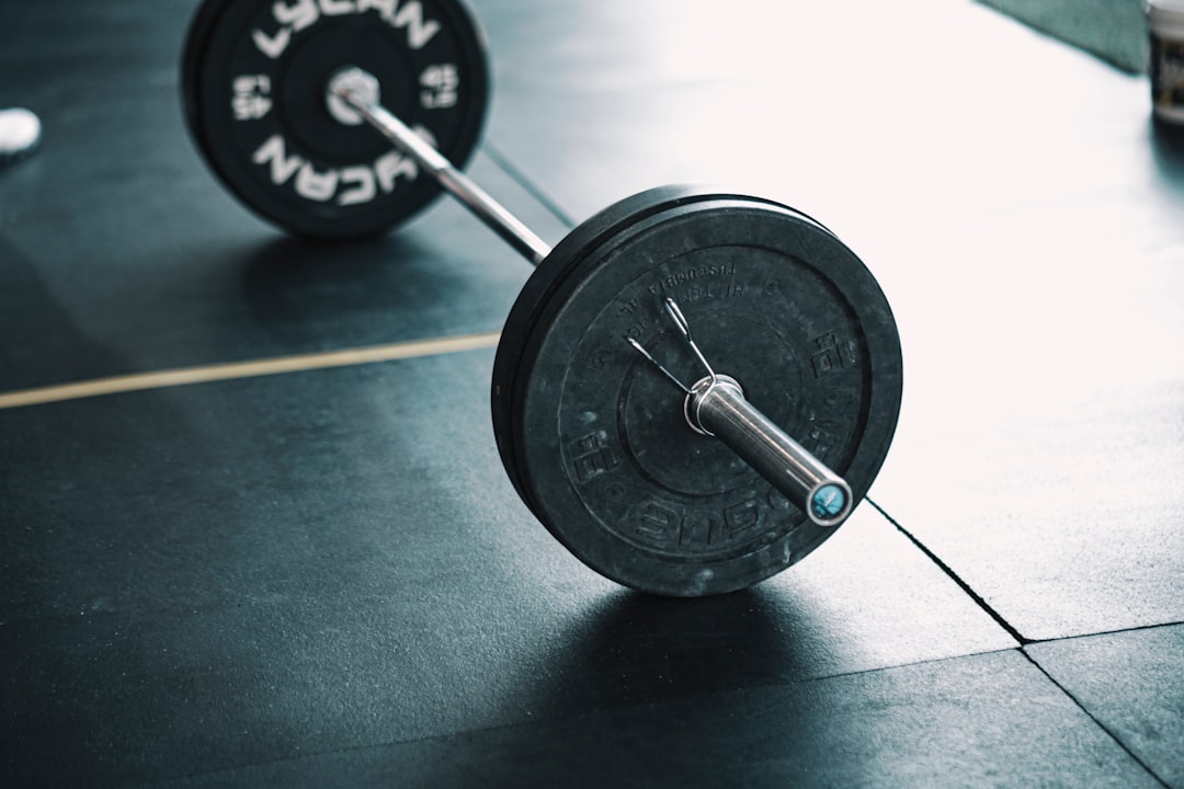Adding weight plates to barbell for progressive overload training